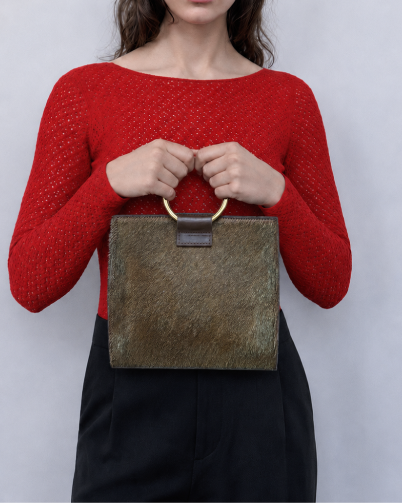 hair on cross body bag with gold ring handles on model wearing red top and black skirt