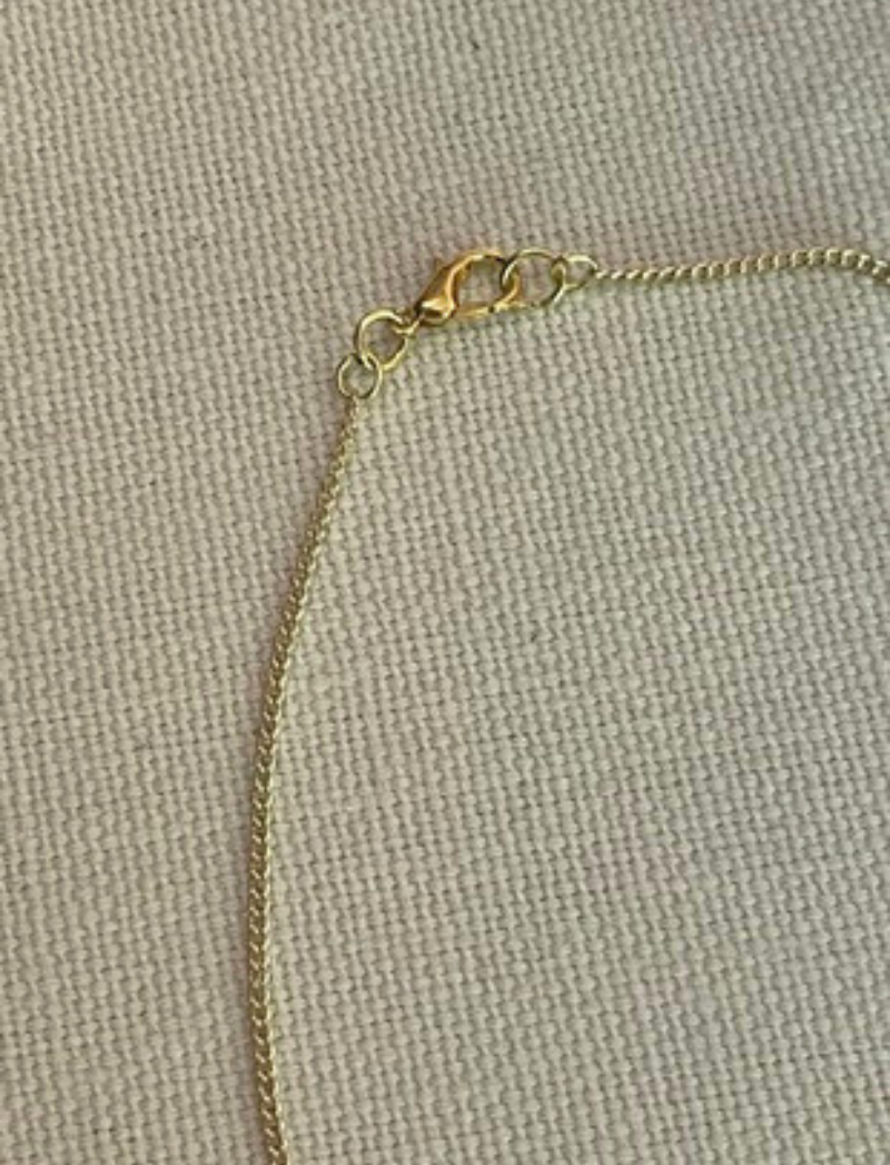 Gold chain necklace with selenite crystal and brass snake charms, detail view